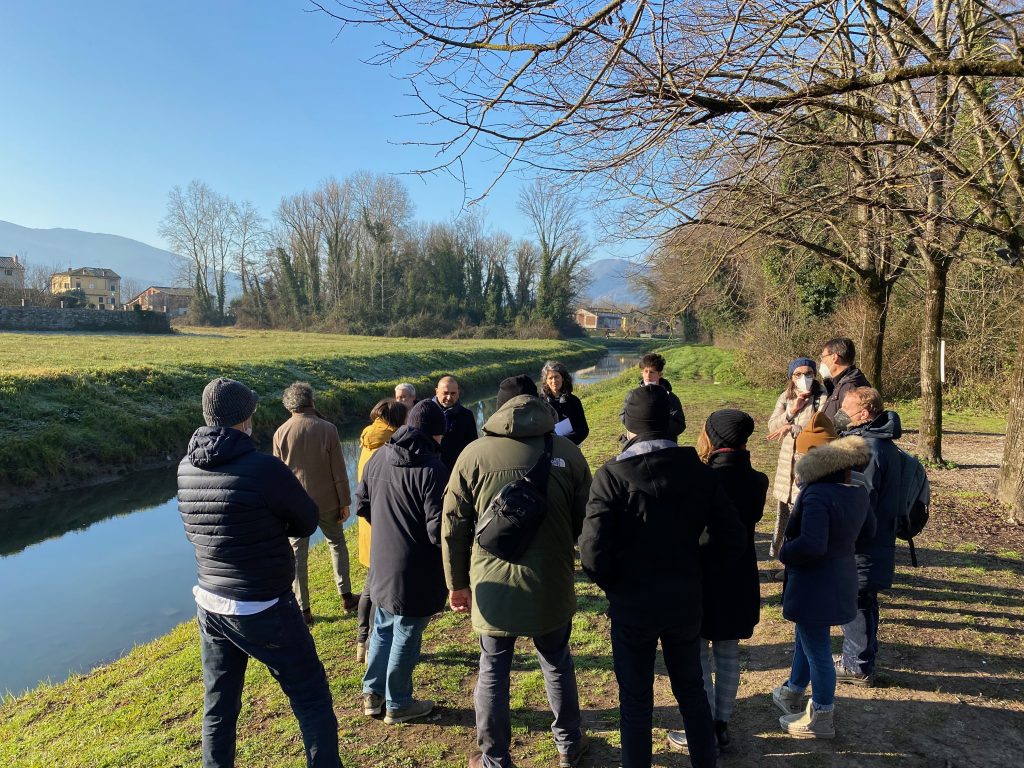 The group listen to the explanation on the canal banks. Is a beautiful winter day with blue sky